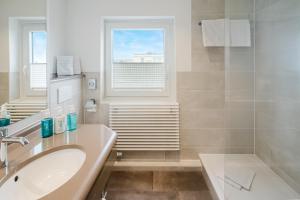 a bathroom with a sink and a tub and a window at Hotel Wiking Sylt in Westerland +59 photos