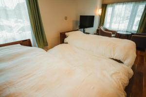 a white bed in a room with a window at 杉 Cedar House in Biei