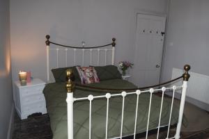 a bedroom with a white bed with a green comforter at Gorffwysfa Hideaway Double 1st floor in Pwllheli +2 photos