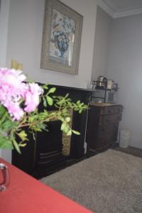 a living room with a fireplace and pink flowers at Gorffwysfa Hideaway Double 1st floor in Pwllheli