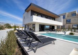 a house with a swimming pool and lounge chairs at Villa Solis in Novalja