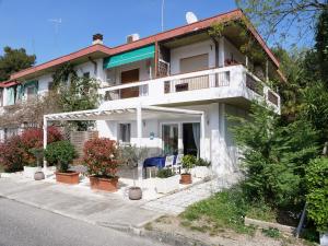 a white house with a balcony and potted plants at Minerva - bilocale indipendente, posto auto e bici in Grado