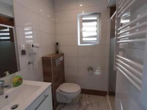a white bathroom with a toilet and a sink at Repos Domki Łeba in Łeba +20 photos
