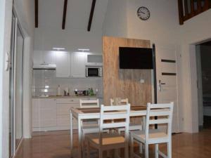 a kitchen with a wooden table and white chairs at Repos Domki Łeba in Łeba