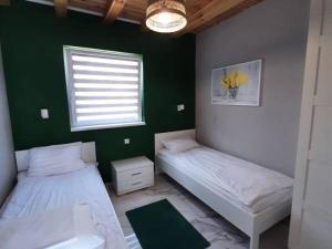 two beds in a room with a green wall at Repos Domki Łeba in Łeba