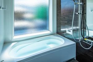 a bathroom with a bath tub next to a window at Galaxy Pool Resort in Takashima