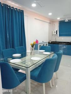 a dining room with a glass table and blue chairs at Coco Villa with Private Pool in Karjat