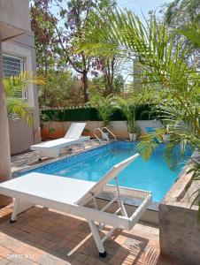 a swimming pool with two lounge chairs next to it at Coco Villa with Private Pool in Karjat