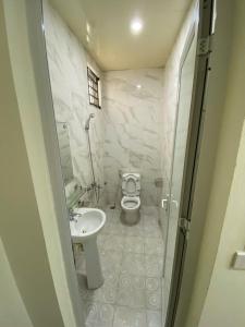 a white bathroom with a toilet and a sink at Khách sạn Tâm An in Ða Gia