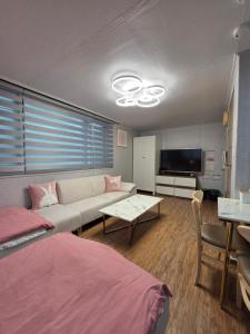 a living room with a couch and a tv at Forêt Guest House Gangnam in Seoul