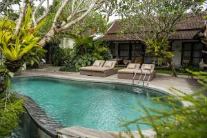 a swimming pool with two lounge chairs and a house at Goya Courtyard Ubud in Ubud