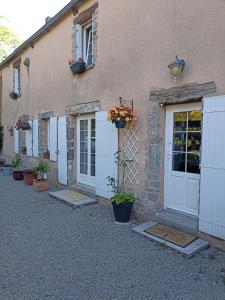 a building with a white door and some potted plants at le lieu jeanne in Auvers
