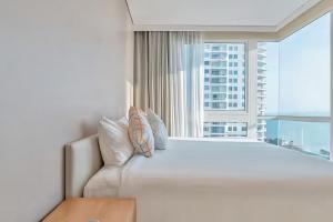 a large white bed in a room with a large window at Veranda Residence Pattaya in Na Jomtien +141 photos