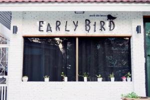 aery bird sign on a store window with potted plants at Early Bird Hostel Ayutthaya in Phra Nakhon Si Ayutthaya