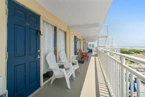 a balcony with white chairs and a blue door at Oceanfront Condo w Heated Pool & Reserved Parking in Wildwood Crest