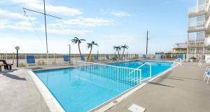 a swimming pool with palm trees and a building at Oceanfront Condo w Heated Pool & Reserved Parking in Wildwood Crest