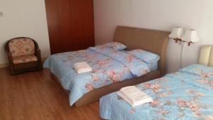 a bedroom with two beds and a chair at T & H Vacation Condo @Marina Court in Kota Kinabalu
