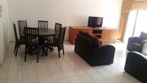 uma sala de estar com uma mesa e cadeiras e uma televisão em T & H Vacation Condo @Marina Court em Kota Kinabalu