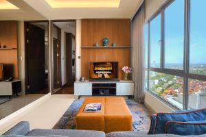 a living room with a fireplace and large windows at Ascott Waterplace Surabaya in Surabaya