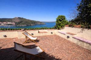 a patio with two benches and a view of the water at Exclusive Villa - Relax - A-C - Stunning View in Porto Ercole