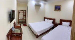 a hotel room with two beds and a tv at Khách sạn Tâm An in Ða Gia