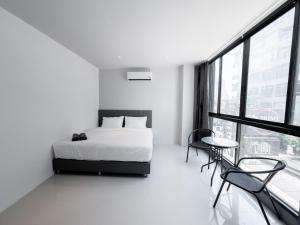 a white bedroom with a bed and a table and chairs at On The Six Studios Pratamnak in Pattaya South