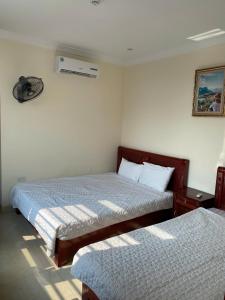 a bedroom with two beds and a air conditioner on the wall at Khách sạn Tâm An in Ða Gia +6 photos