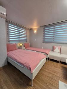 two beds and a couch in a room with windows at Forêt Guest House Gangnam in Seoul