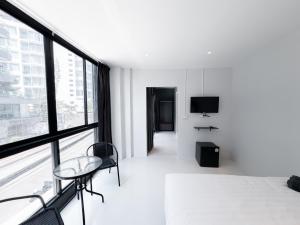 a white room with a chair and a television at On The Six Studios Pratamnak in Pattaya South