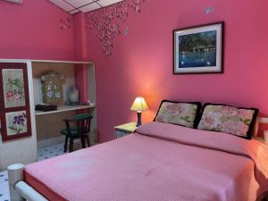 a pink bedroom with a bed with a pink wall at Mairood Resort in Ban Mai Rut