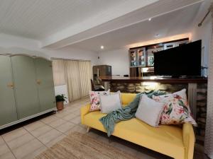 a living room with a yellow couch and a flat screen tv at Merensee in Langebaan