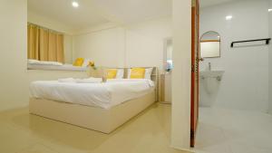 a white bedroom with a bed and a bathroom at Three Monkeys Chaweng Beach in Chaweng