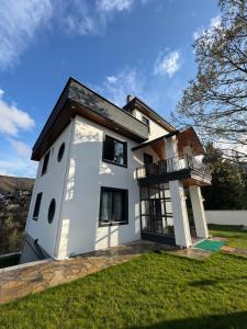 a white house with a balcony on a lawn at Yeşilyurt villa in Sapanca