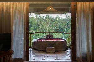 a large bath tub in a room with a window at Kastara Resort in Ubud
