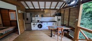 a kitchen with a stove and a table in a room at Ti' Nid Mango Cabane charmante et confortable in Pointe-Noire