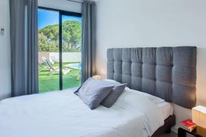 a bedroom with a bed and a large window at Villa casa Luna piscine chauffée vue mer proche centre et plage de Calvi in Calvi