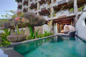 a swimming pool in front of a building at Kastara Resort in Ubud