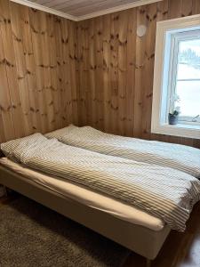 a bed in a room with a wooden wall at Lastølen Snr6 nr2 in Sykkylven