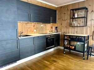 a kitchen with black cabinets and a wooden wall at Lastølen Snr6 nr2 in Sykkylven +6 photos