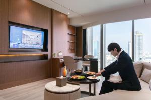 a man sitting on a couch with a plate of food at SZ Canalside Hotel in Bangkok