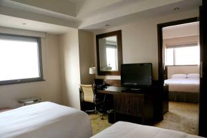 a hotel room with two beds and a desk with a television at Courtyard By Marriott Shanghai Xujiahui in Shanghai