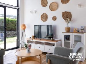 a living room with a tv and a couch and a table at Bird House by PontaNegraAzores in Altares