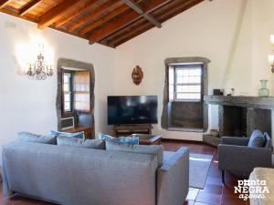 a living room with a couch and a tv at Casa das Vaquinhas by Ponta Negra Azores in Altares
