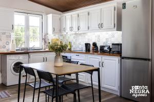 a kitchen with a table and chairs and a refrigerator at The Biscuit House by PontaNegraAzores in Praia da Vitória