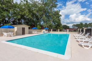 a swimming pool with white chairs and umbrellas at Knights Inn Statesboro in Statesboro