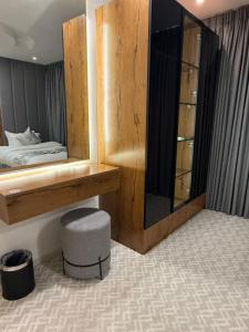 a bedroom with a bed and a mirror and a stool at شقق كورال الفندقية in Buraydah +48 photos