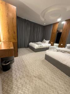 a hotel room with two beds and a desk at شقق كورال الفندقية in Buraydah