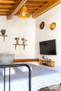 a bedroom with a flat screen tv and a bed at Alojamento Ponta Negra in Biscoitos