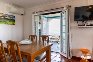 a dining room with a table and chairs and a balcony at Casa da Maresia by PontaNegraAzores in Biscoitos +13 photos