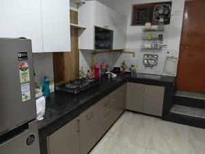 a kitchen with white cabinets and a black counter top at Budget stays in New Delhi